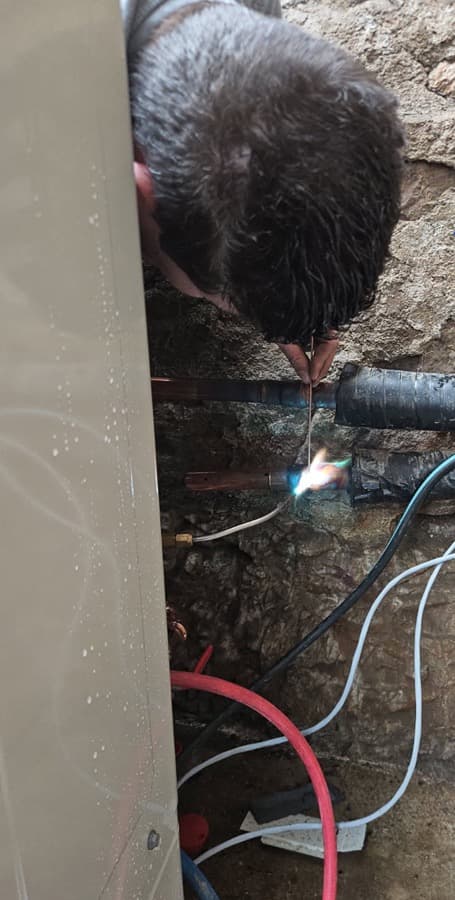 Technicien BP Maintenance réalisant une brasure sur les liaisons d'une pompe à chaleur, à Ternand